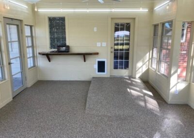 A screened in porch with tile flooring and a ceiling fan.