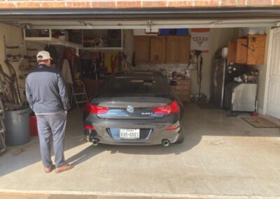 A man standing in front of a car in a garage.