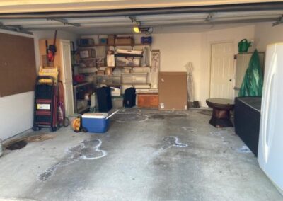 A messy garage with a refrigerator and other items.